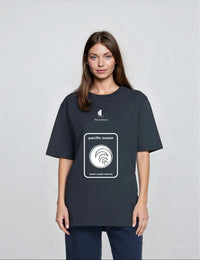 The Sailors T-Shirt με print Pacific Ocean σε απόχρωση DENIM BLUE φορεμένο από καστανή γυναίκα.