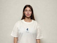 Person wearing a white t-shirt with a logo on a plain background