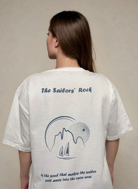 Person wearing a white t-shirt with 'The Sailors' Rock' design and text.